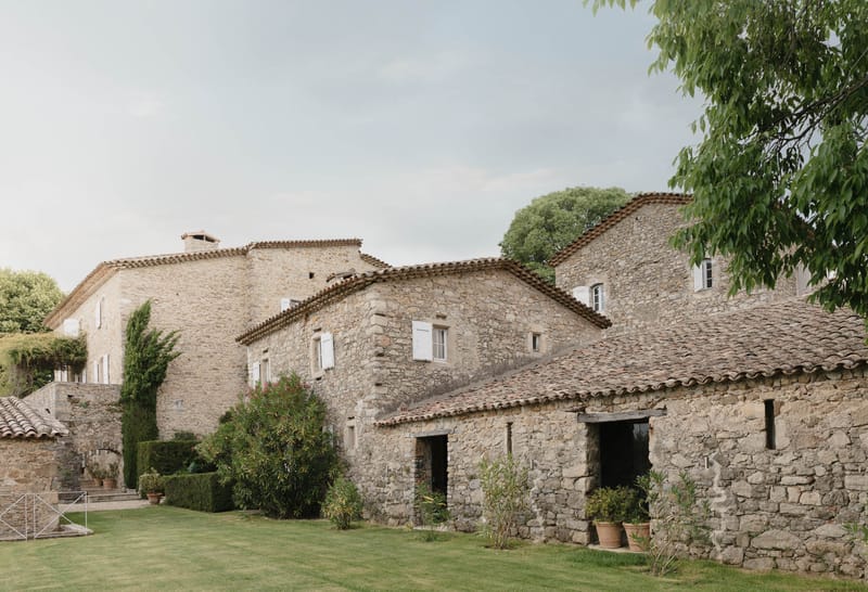 Provencal stone mas farmhouse complex with terracotta roofs, limestone facades, manicured lawn, and cypress trees