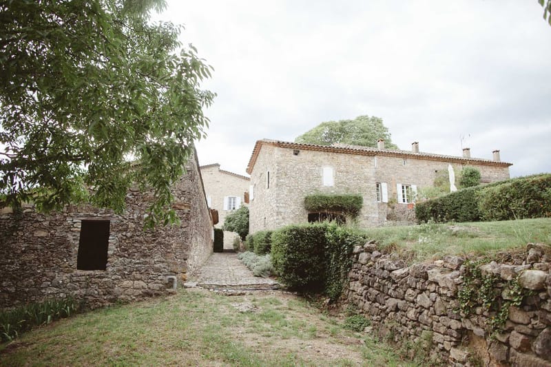 Provencal stone farmhouse complex with terracotta roofs, cobblestone path, and courtyard gardens