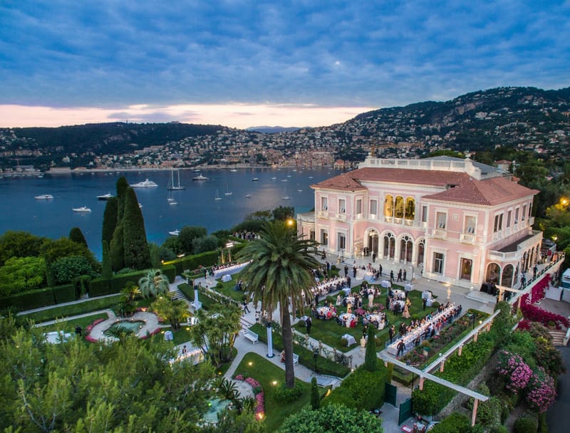 Aerial dusk view of Villa Ephrussi reception on terraced gardens with Riviera bay and yachts
