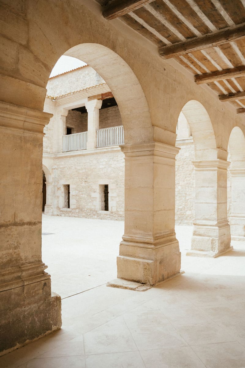 Historic stone colonnade with arches and columns at wedding venue interior
