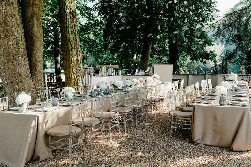 U-shaped reception tables with taupe linen, silver chiavari chairs, and white hydrangea centerpieces