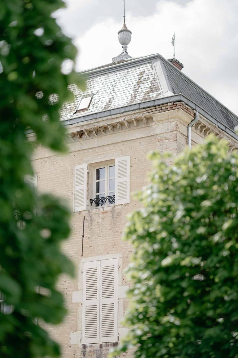 Chateau tower with cream stone louvered shutters wrought-iron balcony and slate mansard roof