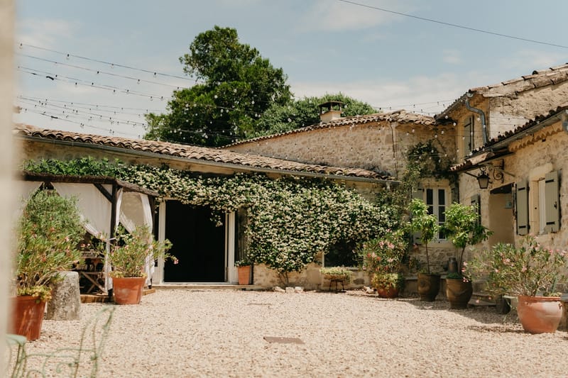 Stone courtyard with festoon lights, jasmine walls and terracotta pots in a French country mas.