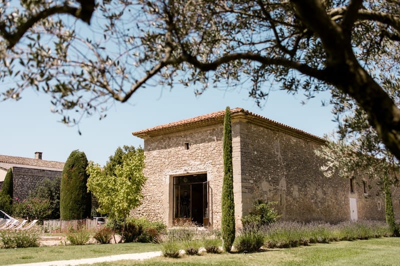 Provencal stone mas with terracotta roof, cypress trees, lavender borders, and manicured lawn framed by olive branches
