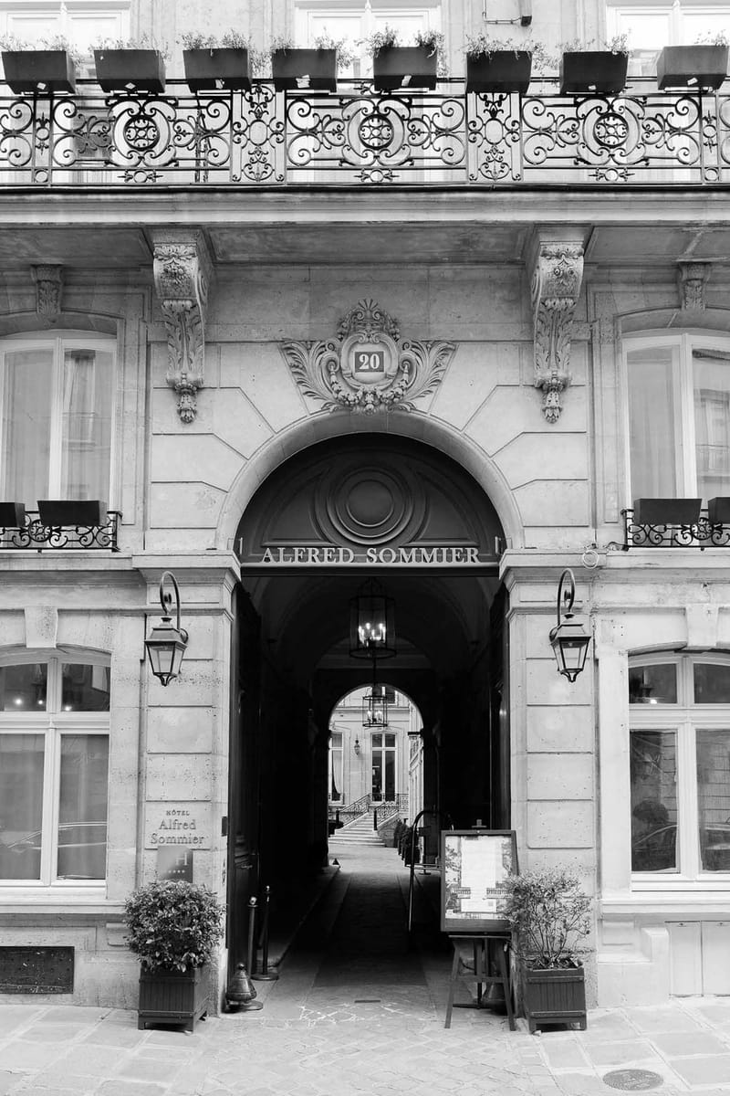Haussmann facade of Hotel Alfred Sommier with arched entrance, wrought-iron balconies, and boxwood in B&W