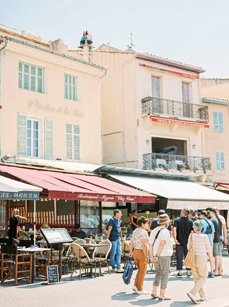 Outdoor restaurant Chez Cesar on a public square in Cassis with red awnings and wicker bistro chairs