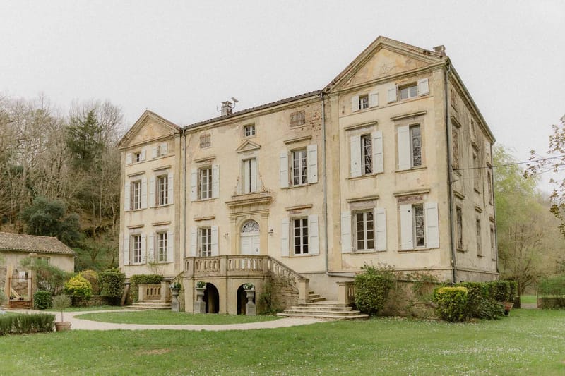 Three-storey French chateau with ochre walls, grey shutters, and grand double staircase entrance