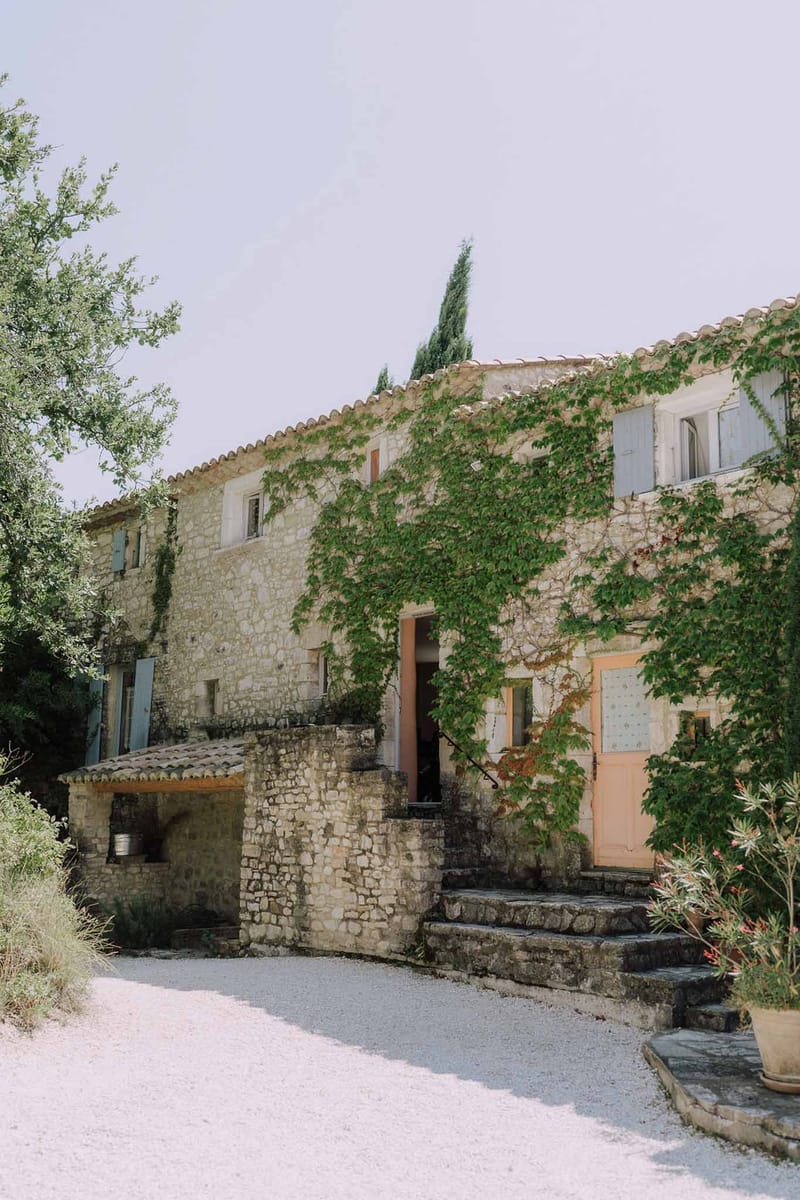 Traditional Provencal stone mas with climbing vines, terracotta roof tiles, and blue-grey shutters