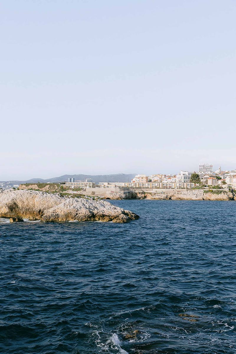 Mediterranean coastal village with white and terracotta buildings on rocky promontory from sea level