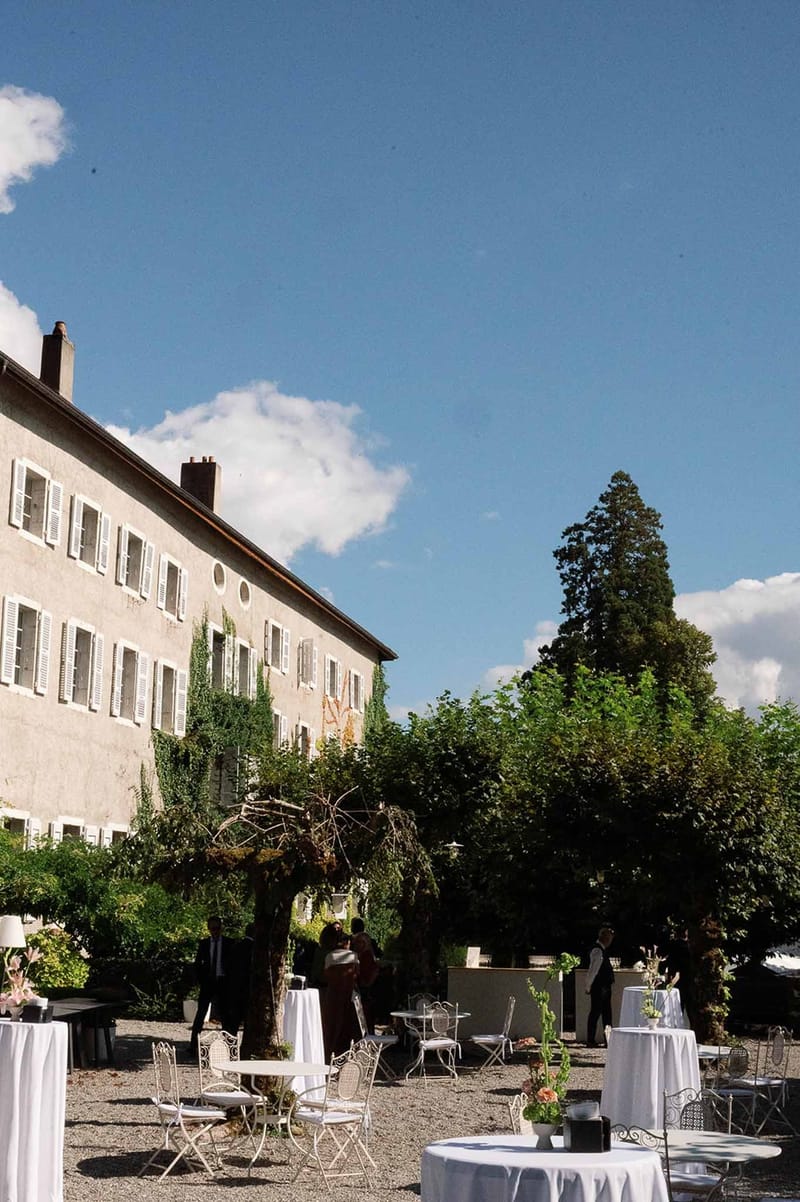 Cocktail tables in courtyard with abbey building behind at Abbaye de Talloires