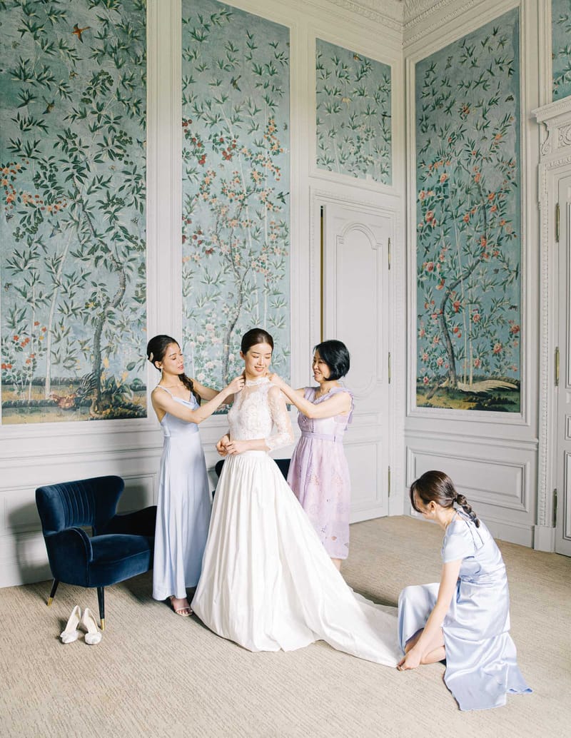 Bride in lace-bodice ivory gown with three attendants in blue and lavender dresses in chinoiserie-paneled room