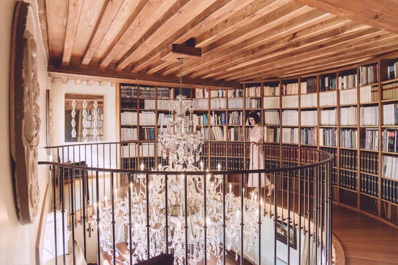 Curved mezzanine library with floor-to-ceiling bookshelves and tiered crystal chandelier