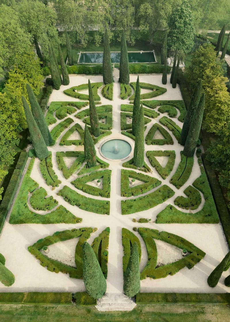 Aerial formal French parterre garden with geometric boxwood hedges central fountain cypress trees and reflecting pool
