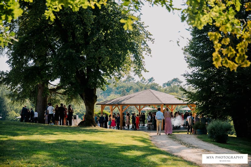 Elevated wide view of guests mingling under a timber pavilion on the grounds of a French country estate
