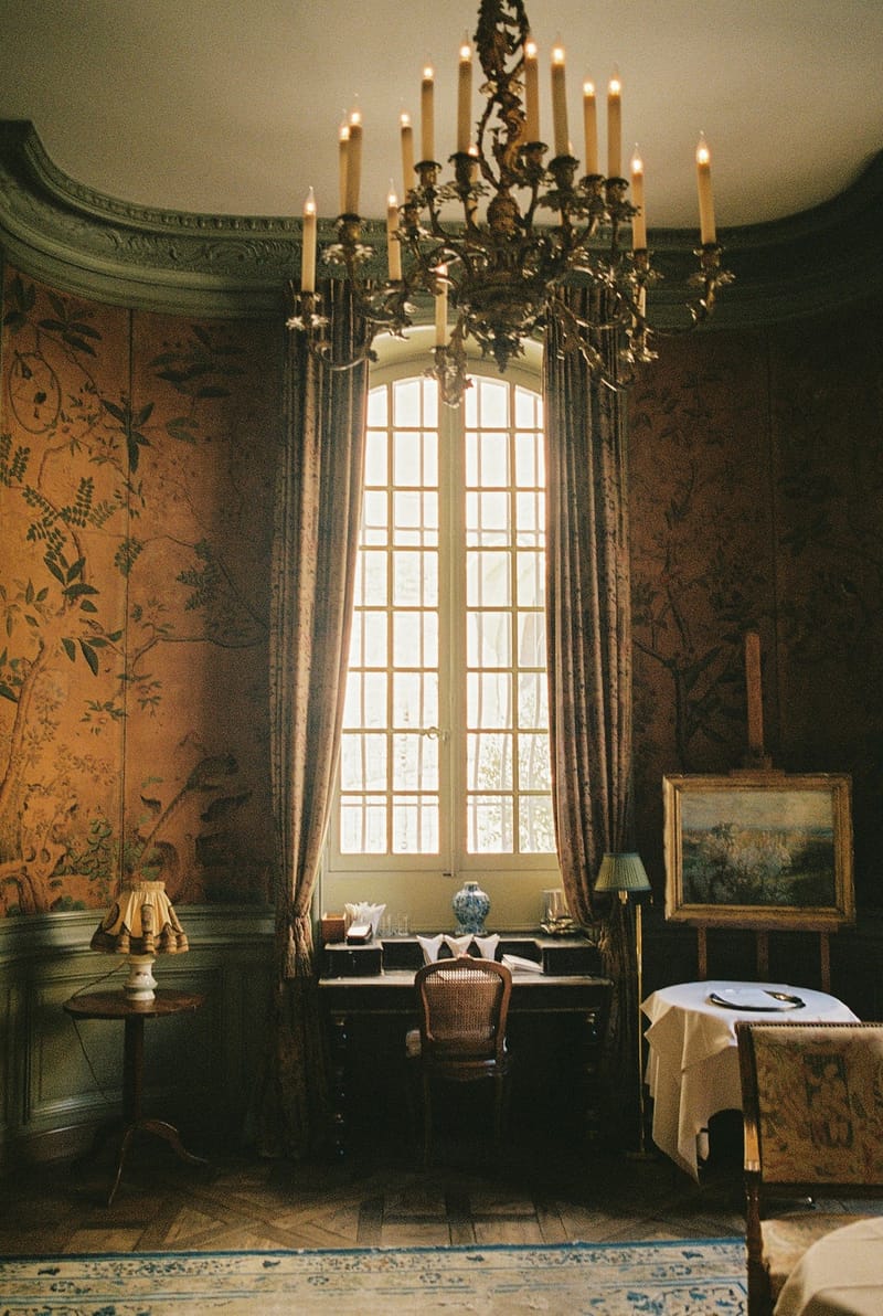 Chinoiserie chateau salon with iron candle chandelier tall draped windows writing desk