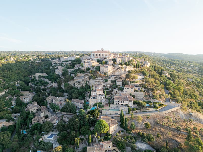 Aerial drone view of Provencal hilltop village with stone buildings and terracotta roofs in Gordes
