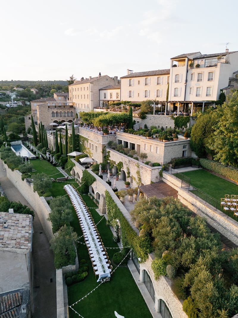 Aerial view of Provencal stone property with banquet tables, fairy lights, and terraced gardens set for reception