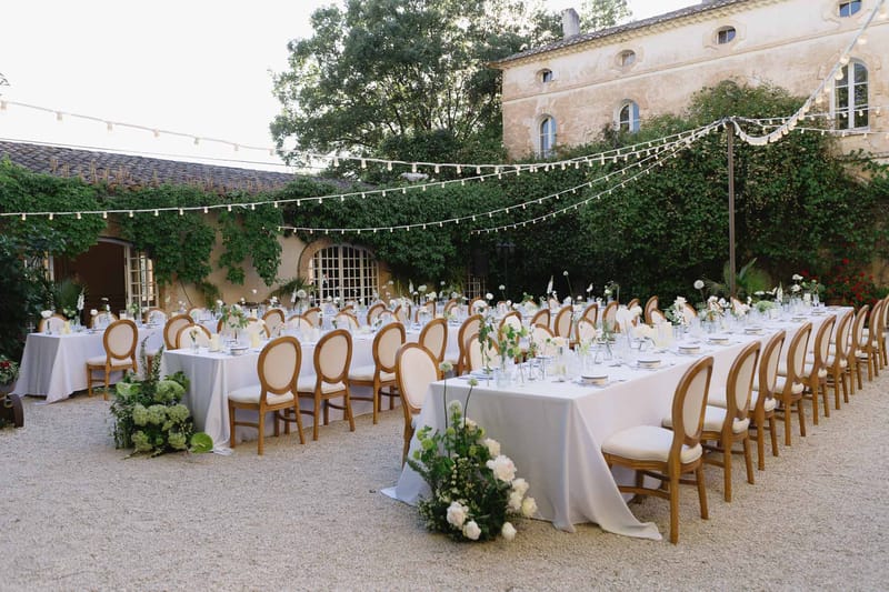 Reception setup at stone mas with grey linen tables, gold Louis chairs, and globe fairy lights