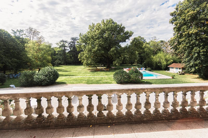 Elevated terrace view over chateau grounds with swimming pool lawn ceremony area and mature trees