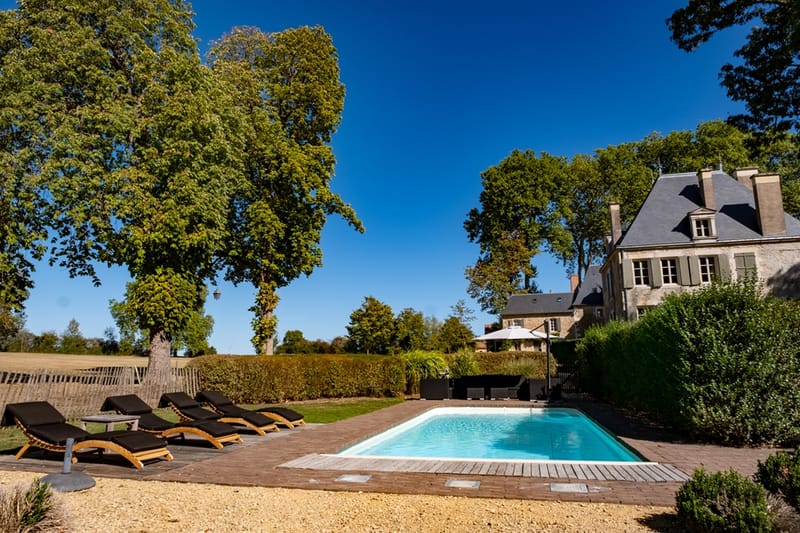 French manor with swimming pool on wooden deck, sun loungers, and slate mansard roof
