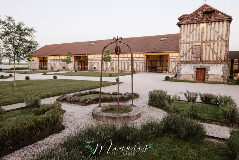 Norman half-timbered barn venue at dusk with formal courtyard garden and antique stone well