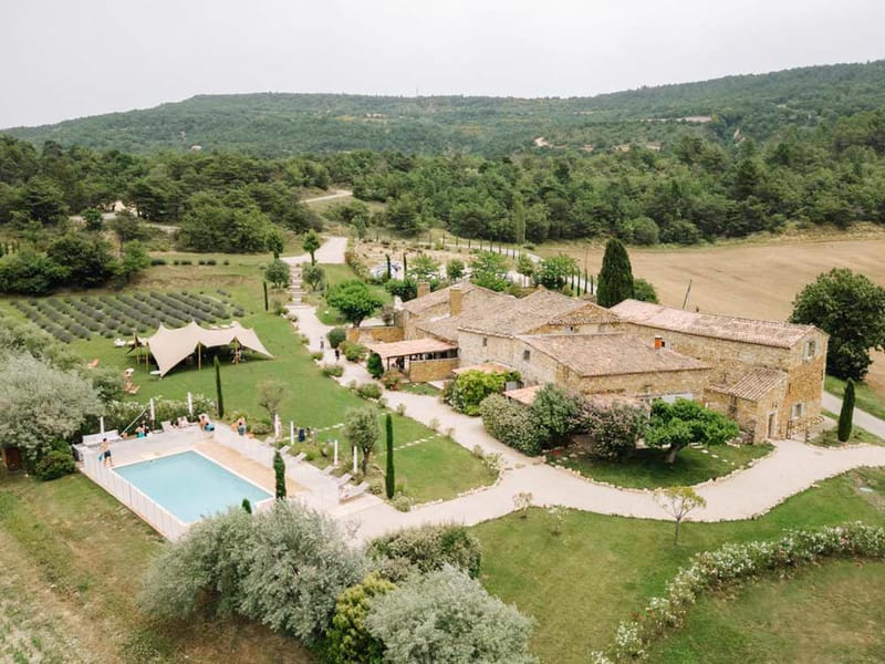 Aerial view of Provencal stone mas with pool, stretch tent, and lavender fields