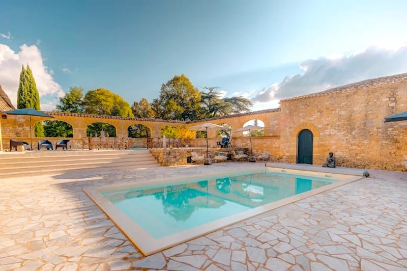 Stone property with rectangular pool, flagstone terrace, and upper stone arcade with arches