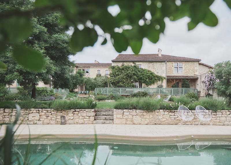 Honey-toned stone mas with pool, Acapulco chairs, and tiered garden viewed through soft foliage