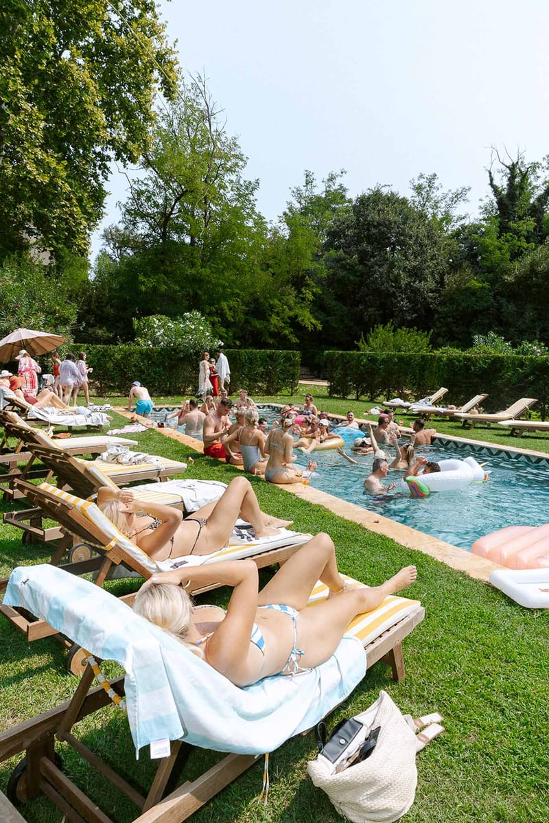 30 guests at pool party with swan inflatable and striped lounger cushions at chateau estate
