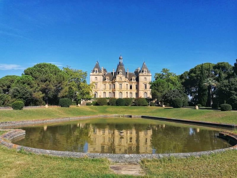 Symmetrical 19th-century chateau with slate turrets and formal reflecting pool on manicured lawn
