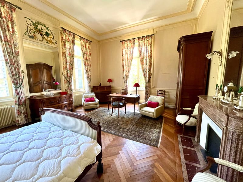 Grand chateau bedroom with herringbone parquet floors, gilded molding, sleigh bed, and marble fireplace