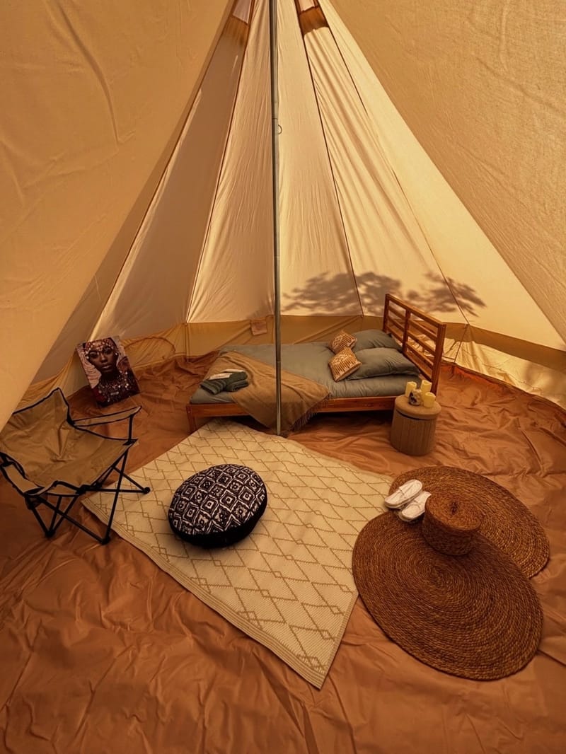 Domaine de la Rose Blanche tipi tent glamping accommodation with a double bed, rugs and floor cushions