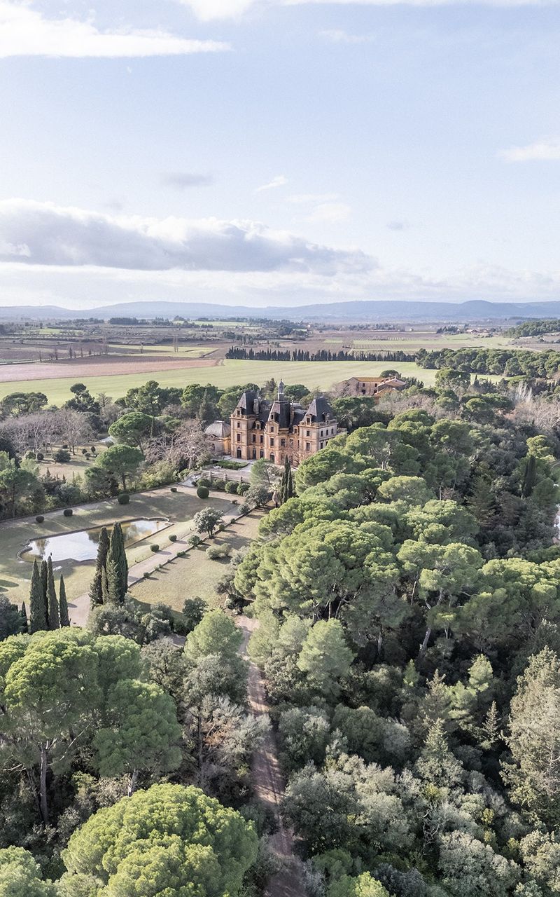 Nineteenth-century chateau with terracotta roof nestled amid cypress trees and manicured grounds overlooking Tuscan-style countryside.