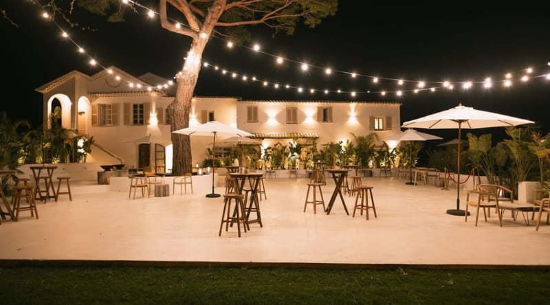 The terrace set for an evening reception under string lights