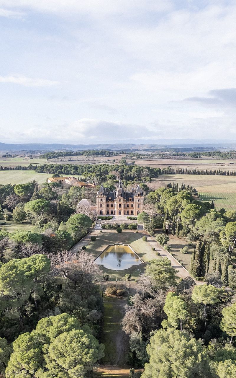 Aerial view of Château du Terral, formal pool and grounds within a wide rural landscape