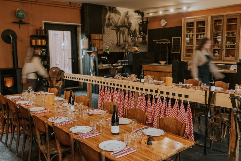 La Cantine du Vendangeur dining room styled with red-check napkins, wine racks and a vintage horse-and-carriage mural