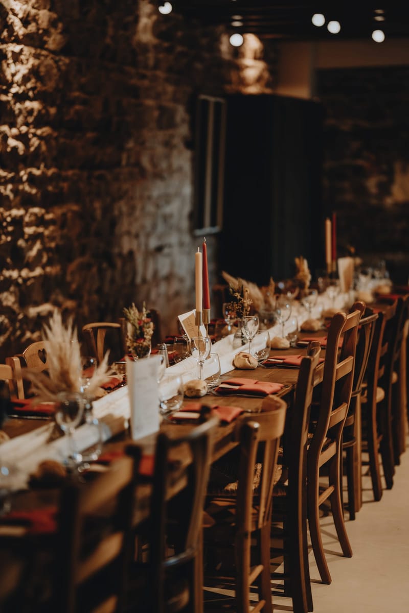 Table setting with taper candles, dried pampas grass and rust-coloured napkins in the stone reception hall
