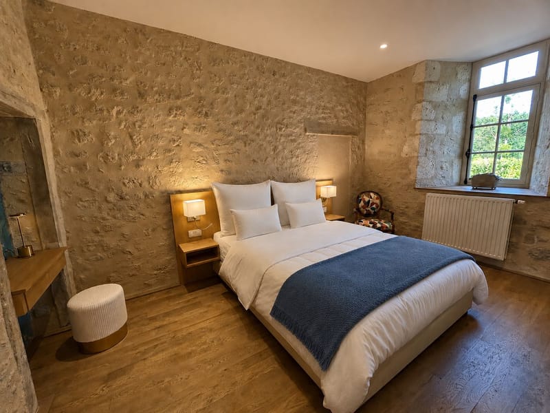 Guest bedroom with an exposed stone wall, oak floor and a blue throw