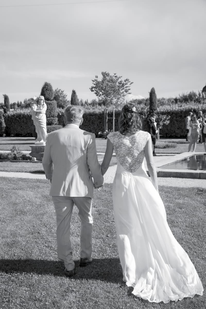 A bride walking through the gardens with her father before the ceremony