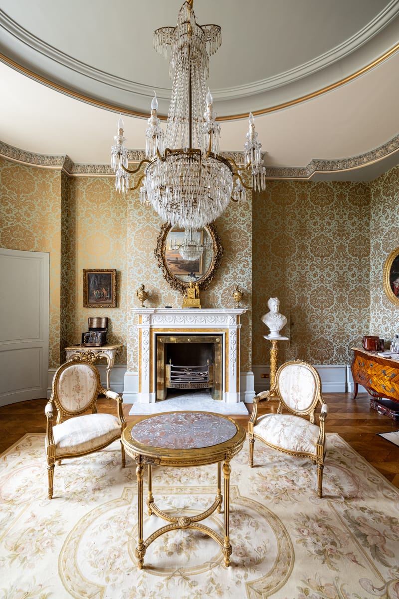 A salon at Château Changeux with a crystal chandelier and gilded furniture
