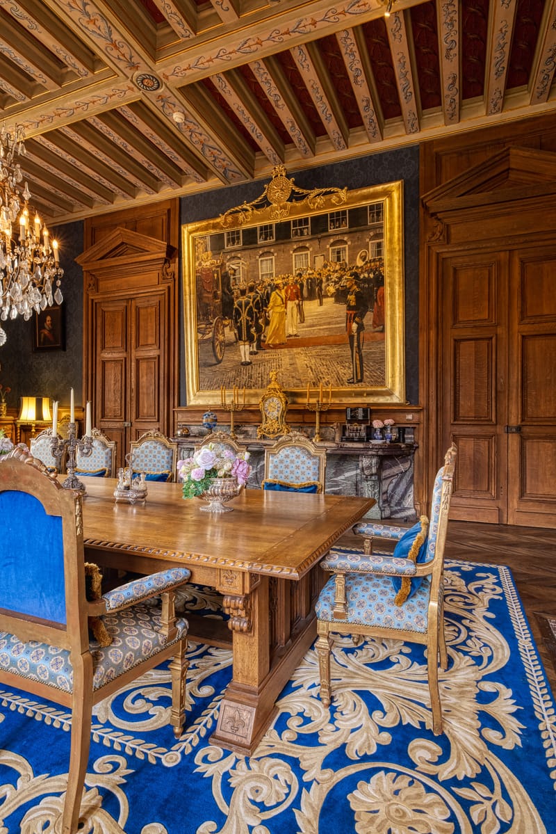 The dining room at Château Changeux, set with a long table beneath a painted ceiling