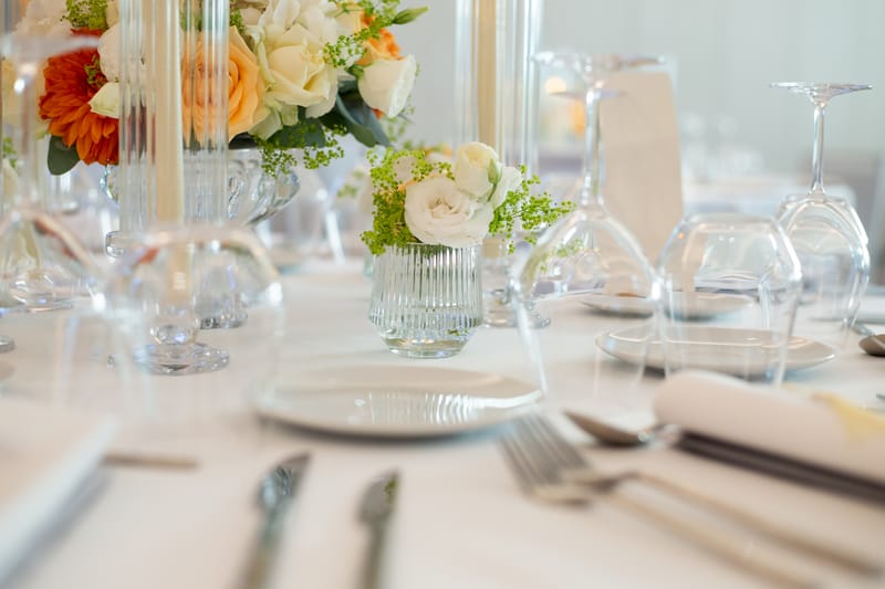 Wedding table with white roses in ribbed glass vases and stemmed glasses