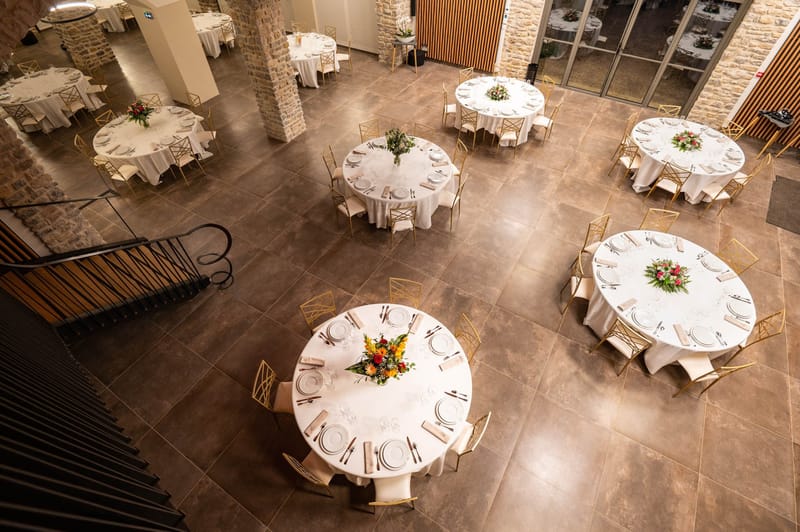 Domaine de Blacailloux bastide reception hall aerial view with round tables gold chairs and floral centerpieces