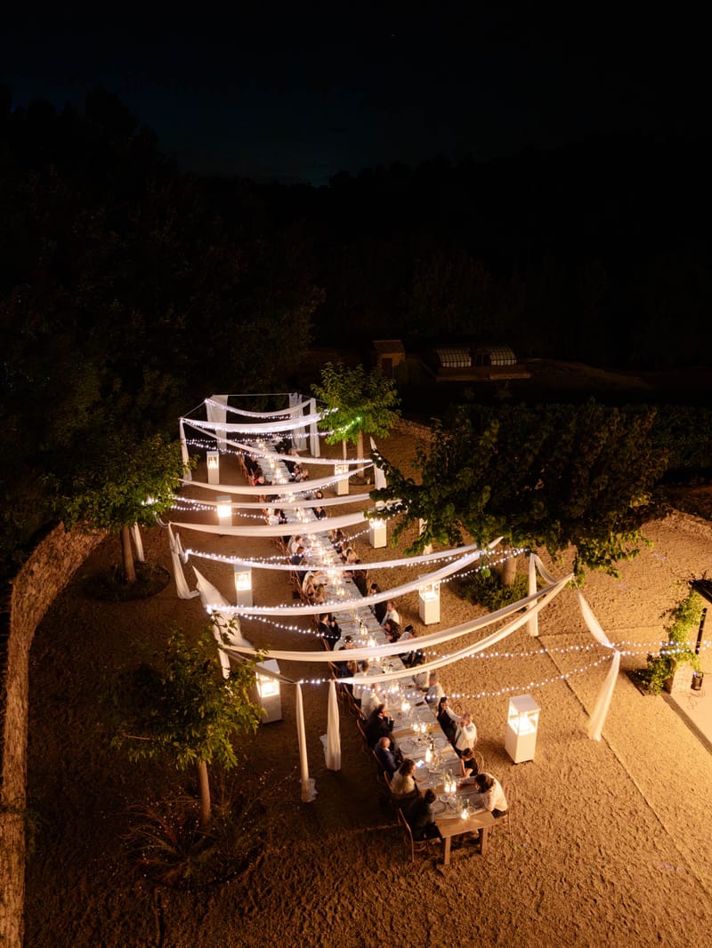 Aerial overhead of festoon-lit evening reception aisle with white drapes at Domaine de Blacailloux