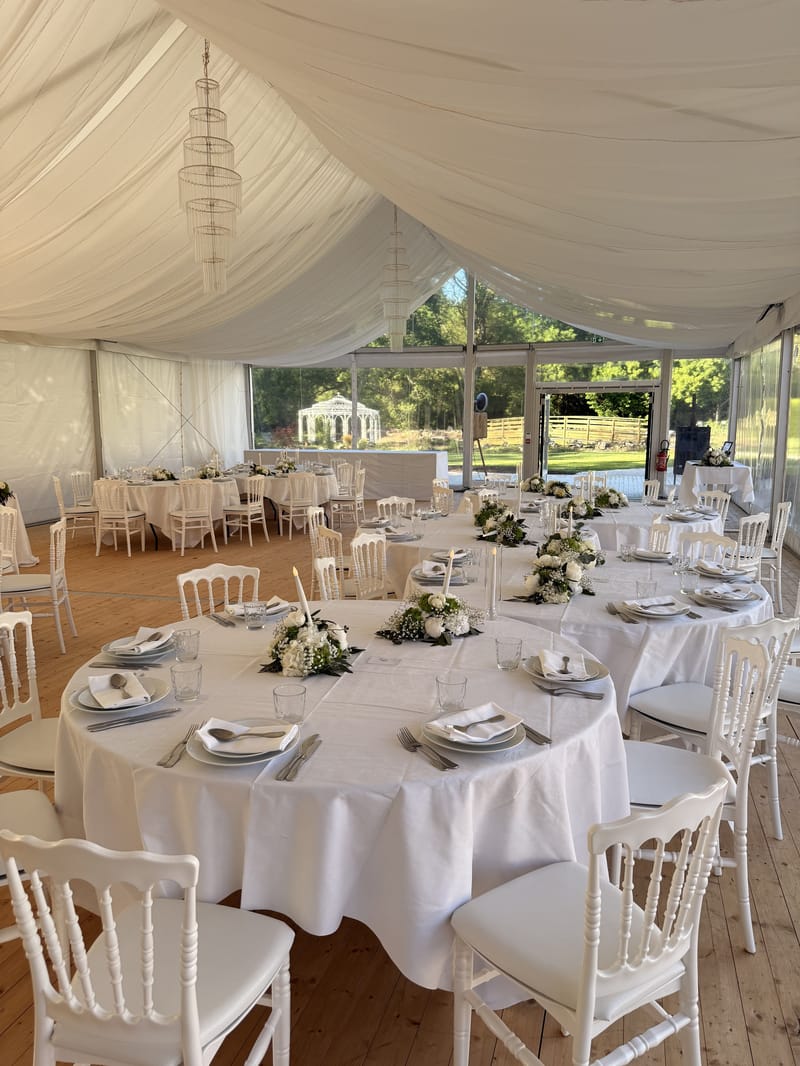 Round tables in white linen under draped fabric and crystal chandeliers in the Pavillon du Parc marquee