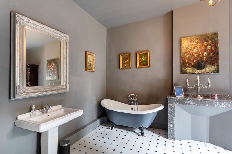 A bathroom with a clawfoot bathtub, pedestal basin and marble fireplace