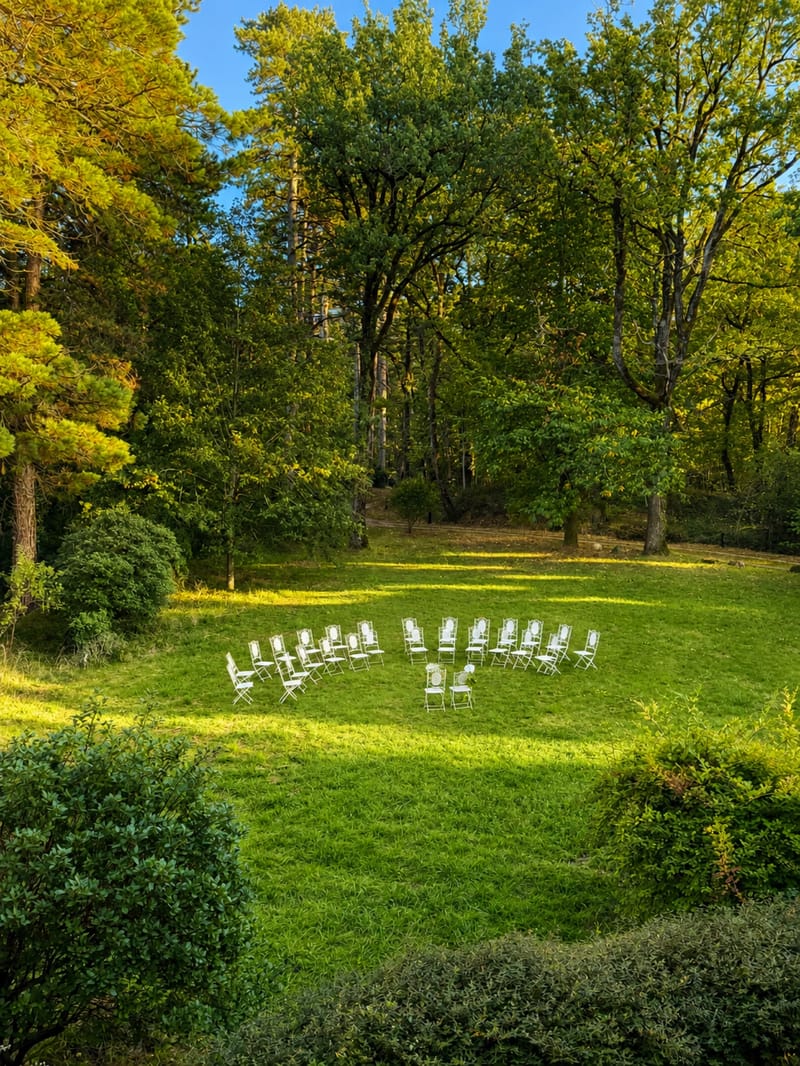 Ceremony chairs arranged in a semicircle on the lawn, framed by mature trees.