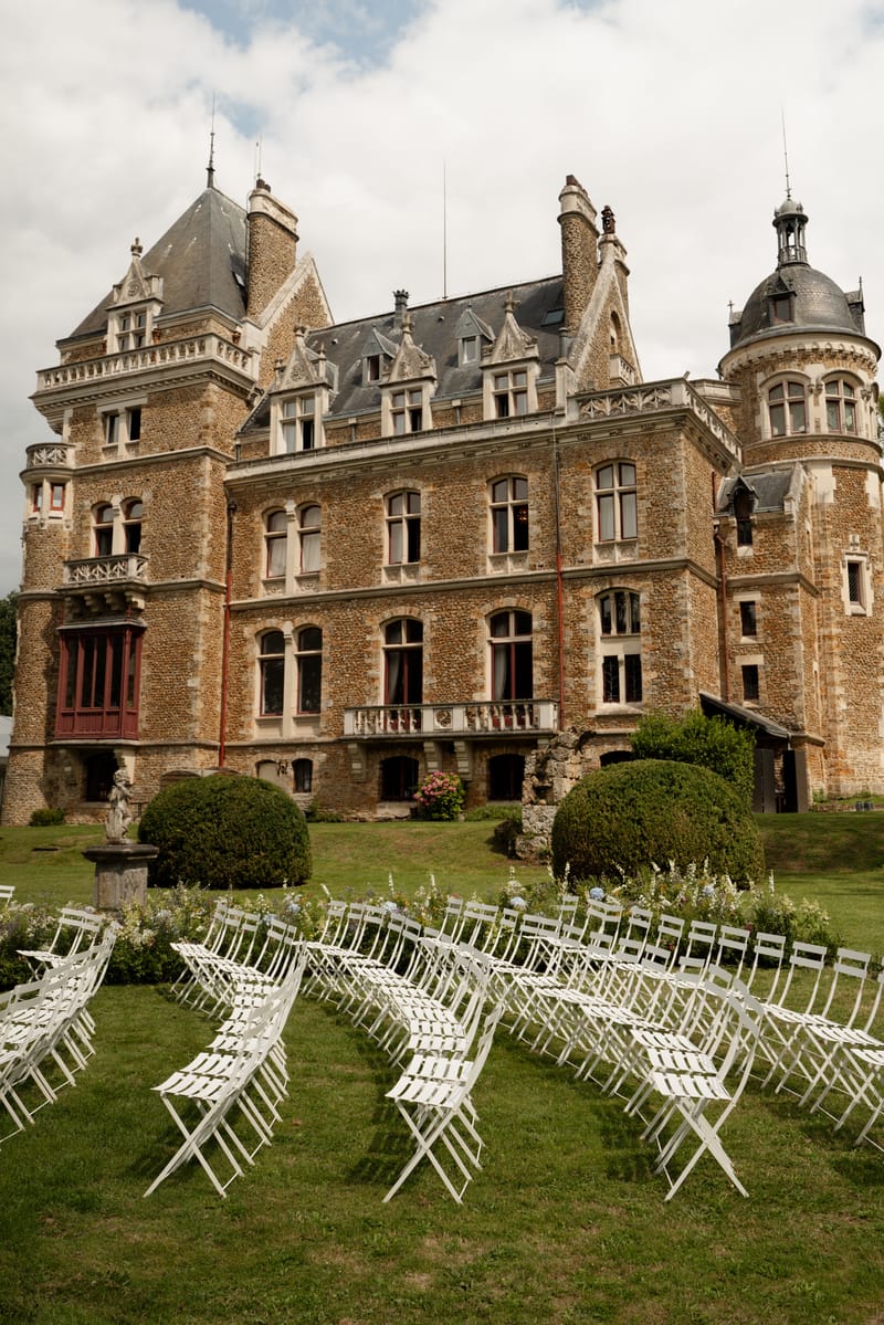 Front facade of Château de Méridon with rows of white outdoor ceremony chairs in front