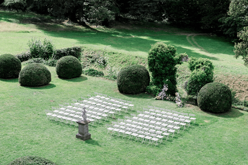 Aerial view of outdoor ceremony seating arranged in a formal garden with topiary at Château de Méridon