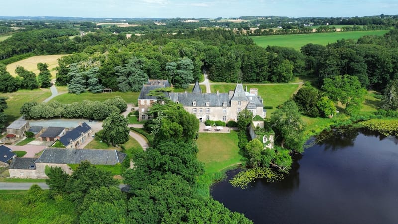Aerial view of Chateau du Pordor from the west, with the farm buildings, parkland and lake